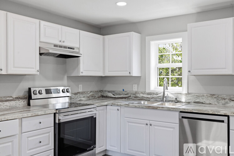 A kitchen with white cabinets and a marble countertop.
