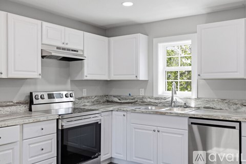 A kitchen with white cabinets and a marble countertop.