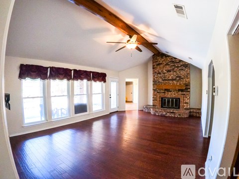 A spacious living room with wood flooring and a stone fireplace.
