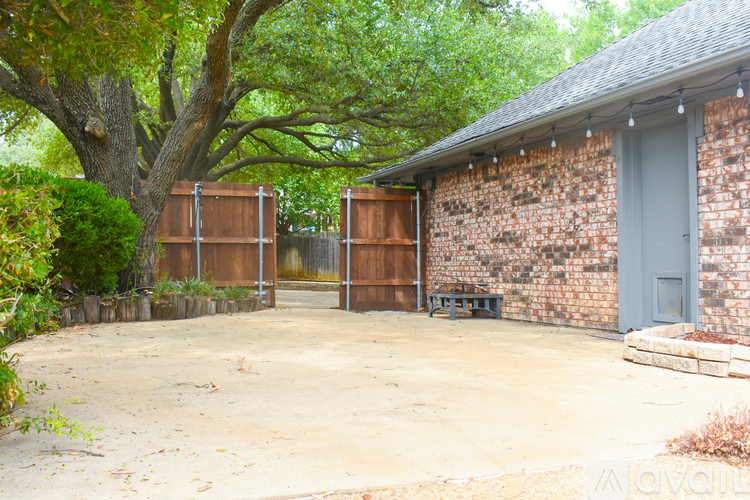 A backyard with a tree, a brick building, and a fence.