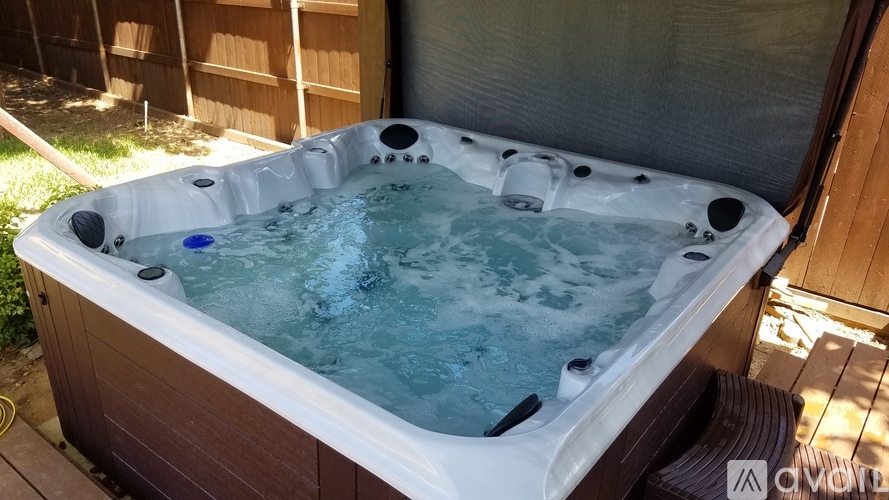 A hot tub with a blue control button is surrounded by a wooden deck.