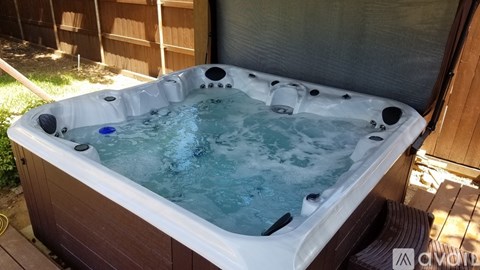 A hot tub with a blue control button is surrounded by a wooden deck.