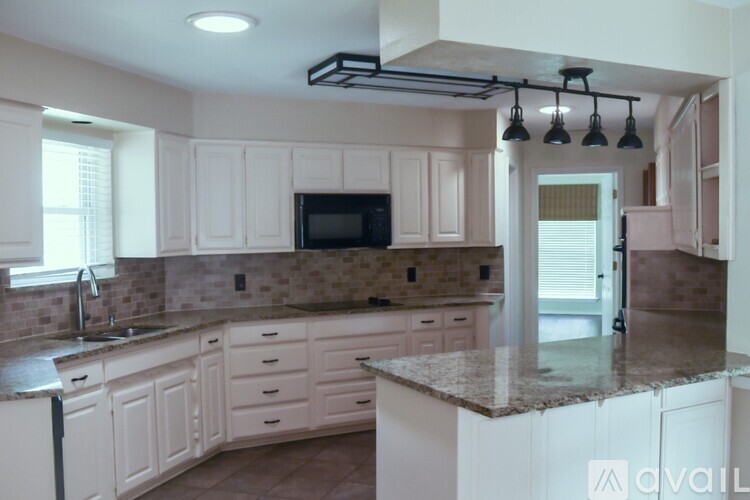 A kitchen with white cabinets and a granite countertop.