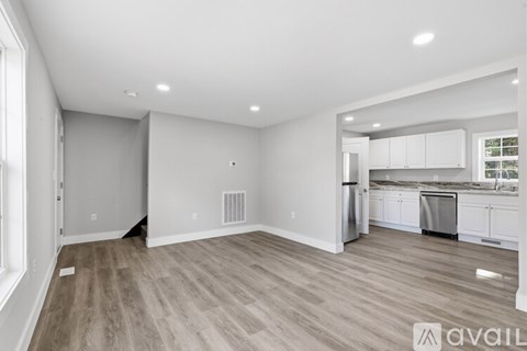 A spacious kitchen with white cabinets and a dining area.