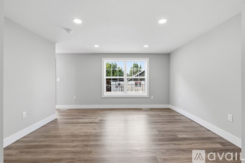 A spacious room with wooden flooring and a large window.