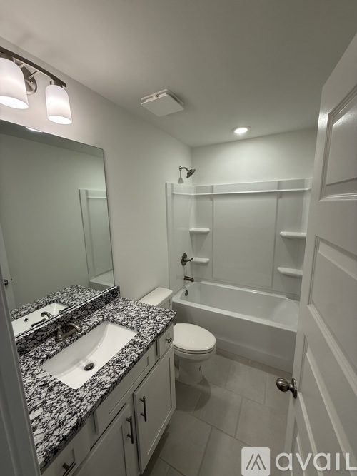 A bathroom with a sink, mirror, toilet and bathtub.