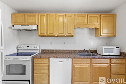 A kitchen with wooden cabinets and a white dishwasher.