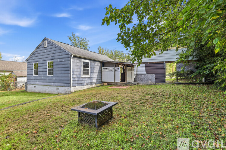 A blue house with a hot tub in the yard.