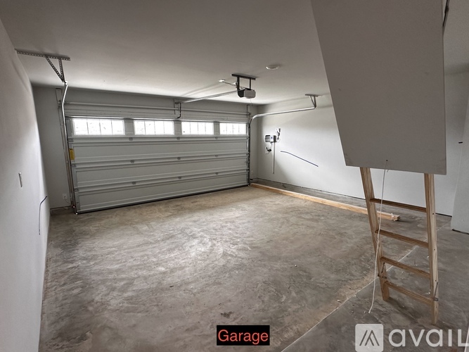 A spacious garage with a closed white door and a ladder.