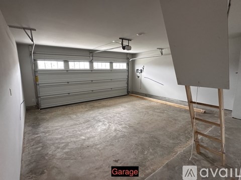 A spacious garage with a closed white door and a ladder.