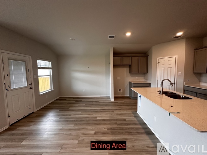 A dining area with a wooden floor and a counter with a sink.