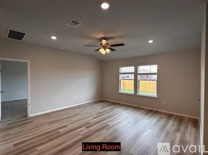 A living room with a ceiling fan and two windows.