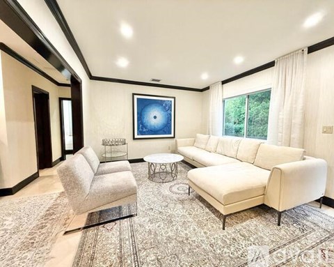 A living room with a large painting and a white sofa.
