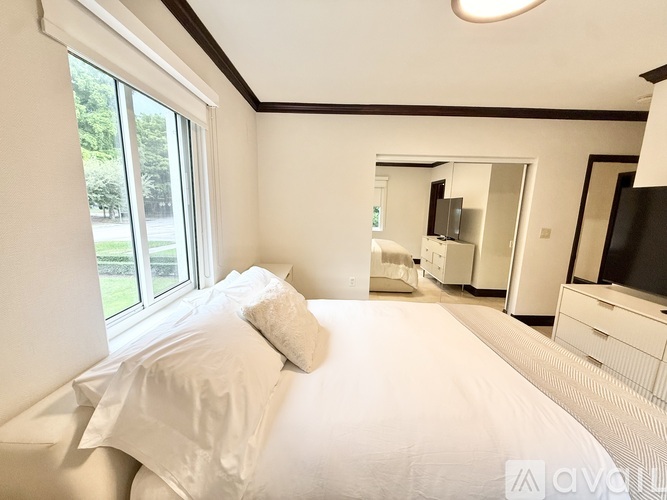 A white bedroom with a large bed and a television.