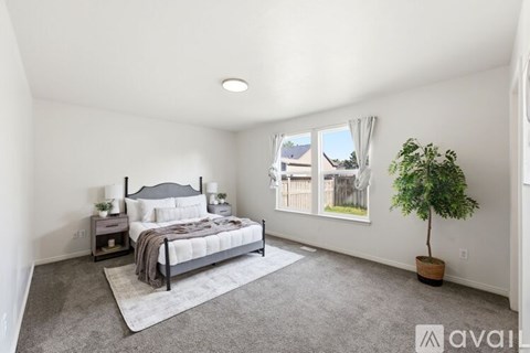 A bedroom with a large bed and a window overlooking a fence.