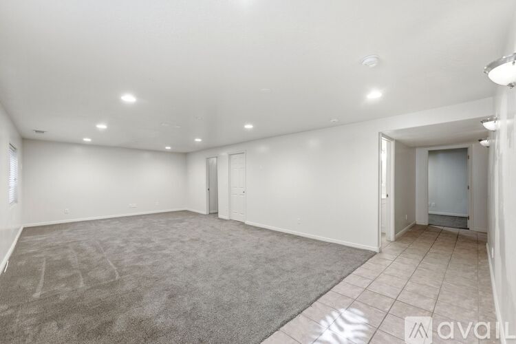 A spacious room with a grey carpet and white walls.