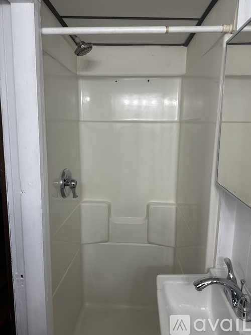 A small white bathroom with a white shower and sink.