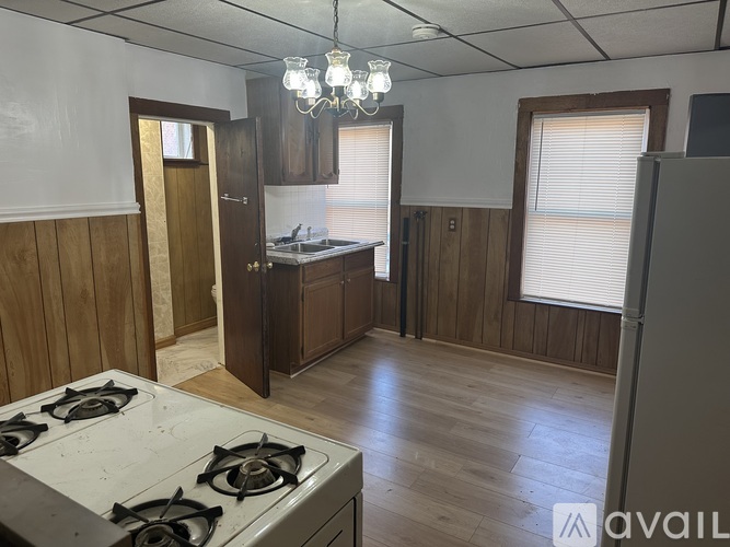 A kitchen with a white stove top oven and wooden cabinets.