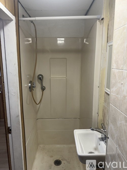 A small white sink is in a small white shower stall.