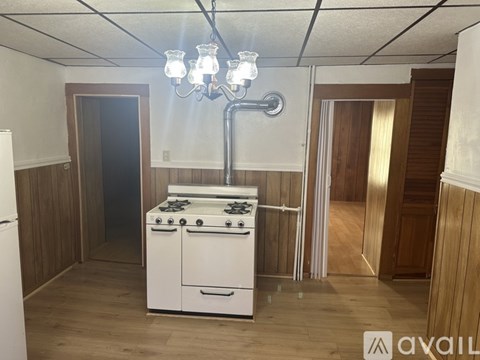A white gas stove is in a room with wooden walls and a chandelier.