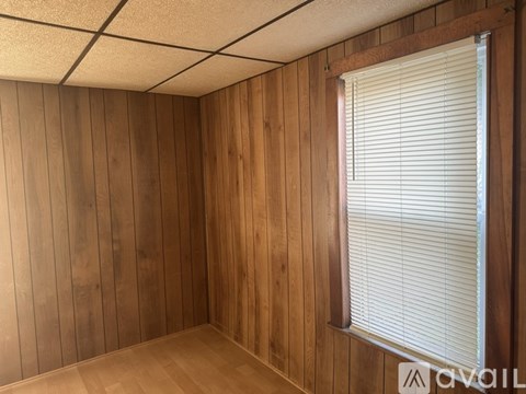 A room with wooden walls and a window with blinds.