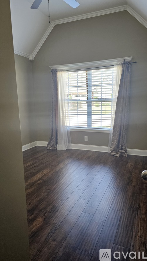 A room with wooden floors and a window with curtains.