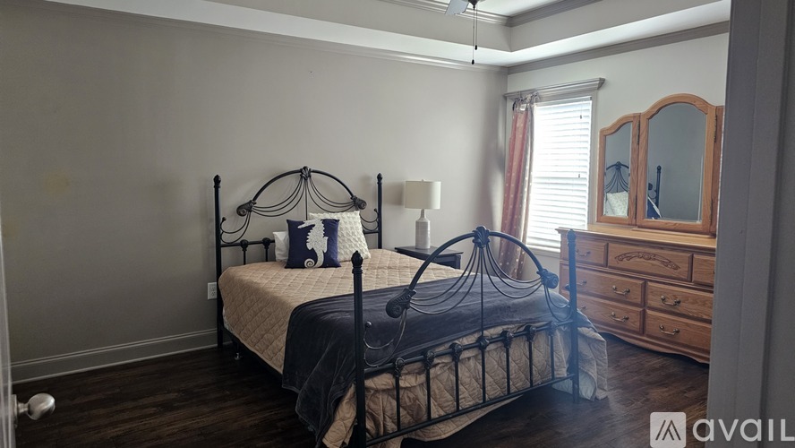 A bedroom with a black metal bed frame and a wooden dresser.
