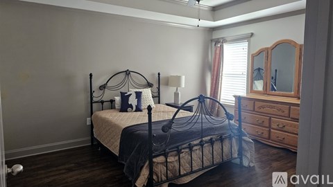 A bedroom with a black metal bed frame and a wooden dresser.