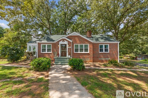 A red brick house with a green lawn in front.