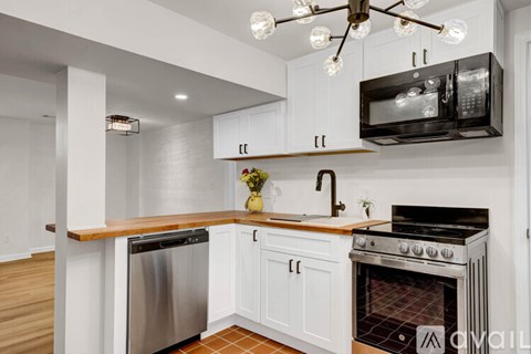 A kitchen with white cabinets and a black microwave above the stove.