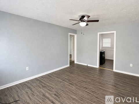 A room with a ceiling fan and wooden flooring.