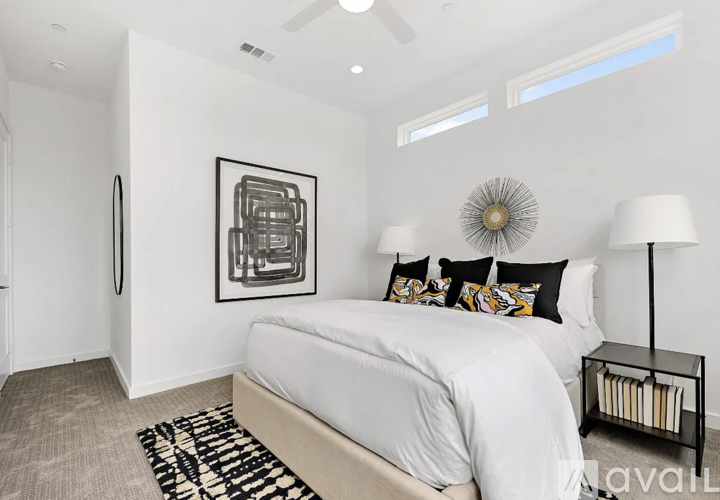 A bedroom with a large bed, a ceiling fan, and a framed picture on the wall.