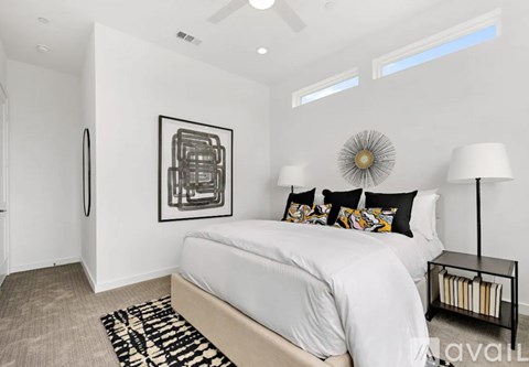 A bedroom with a large bed, a ceiling fan, and a framed picture on the wall.