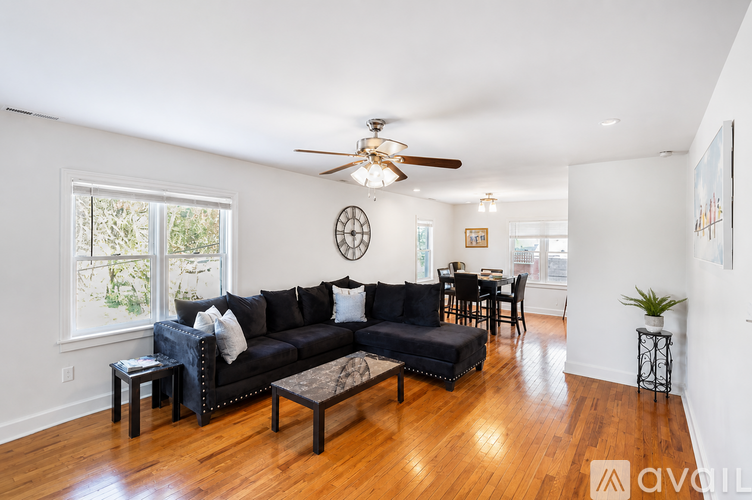 A living room with a black couch and a ceiling fan.