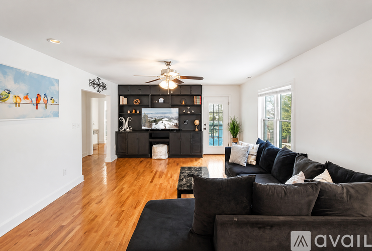 A living room with a black couch and a painting on the wall.