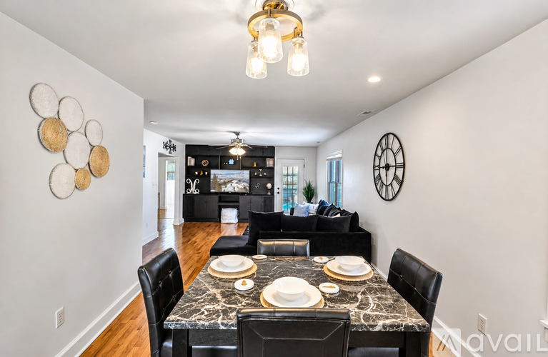 A dining room with a table set for two and a chandelier hanging from the ceiling.