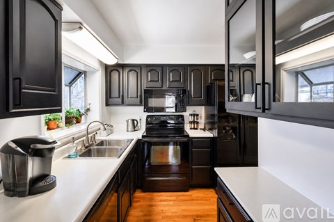 A modern kitchen with dark wood cabinets and stainless steel appliances.