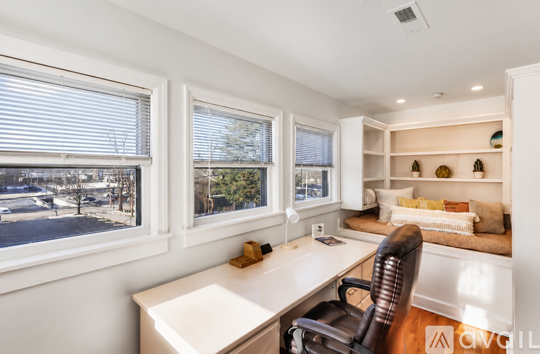A room with a desk, chair, and window overlooking a street.