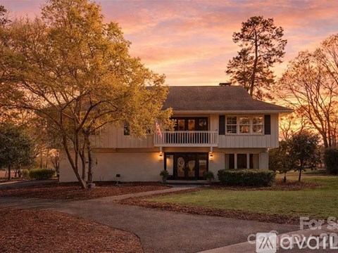 A house with a front yard and a tree with yellow leaves.