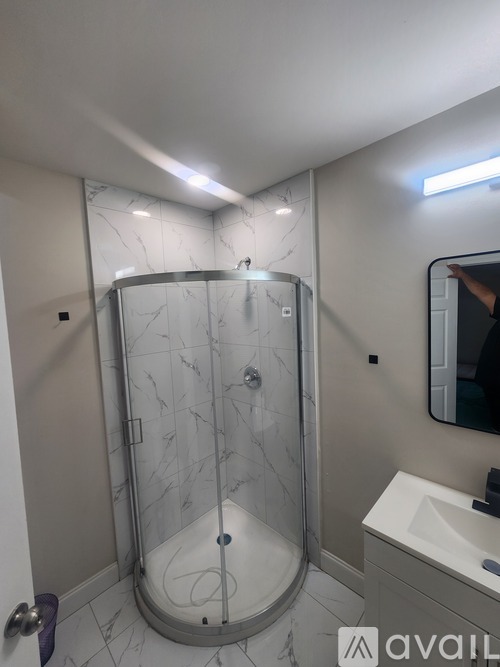 A bathroom with a marble shower and a white sink.