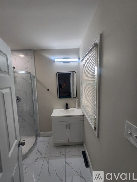 A bathroom with a sink, mirror, and shower.