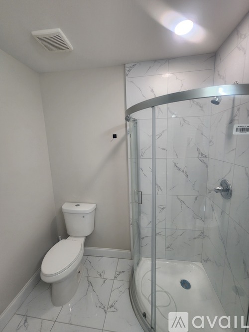 A white toilet sits next to a walk-in shower with a glass door.