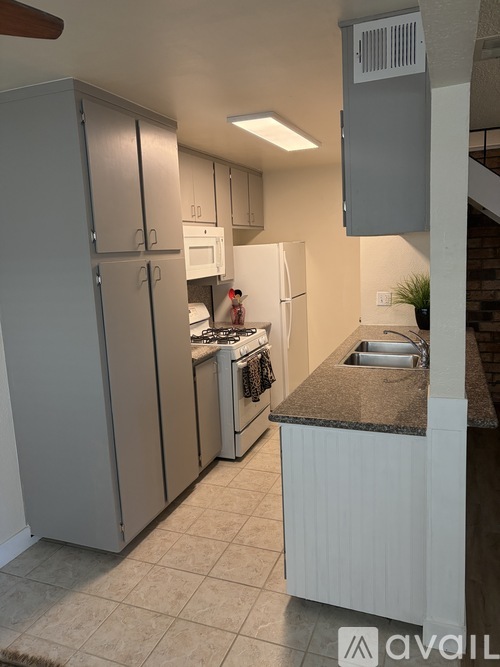 A kitchen with a refrigerator, sink, and cabinets.