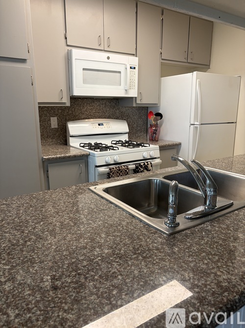 A kitchen with a granite countertop and a stainless steel sink.