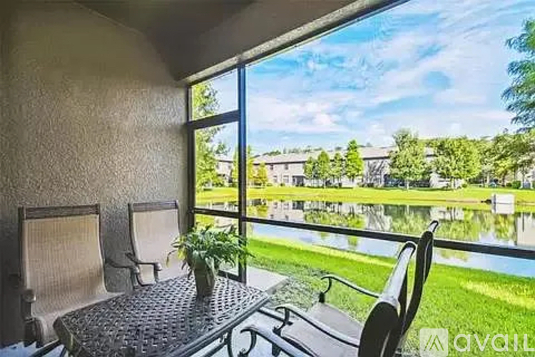 A patio with a table and chairs overlooking a grassy area.