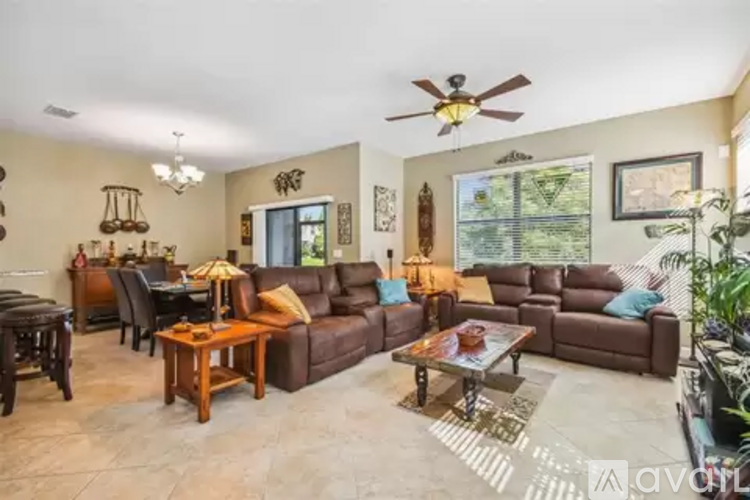 A living room with brown leather furniture and a ceiling fan.