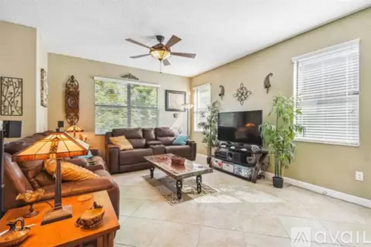A living room with a brown leather couch, a coffee table, and a ceiling fan.