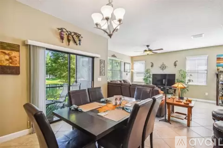 A dining room with a table set for six and a chandelier hanging from the ceiling.