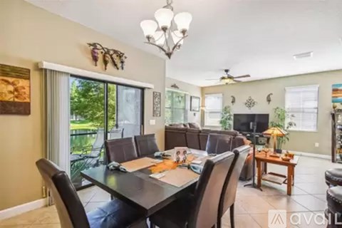 A dining room with a table set for six and a chandelier hanging from the ceiling.