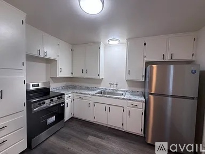 A kitchen with white cabinets and a stainless steel refrigerator.